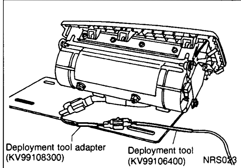 Air bag module bracket clamped in a vise with the deployment tool adapter (SST KV99108300) and deployment tool (SST KV99106400) connected to the module's connector.