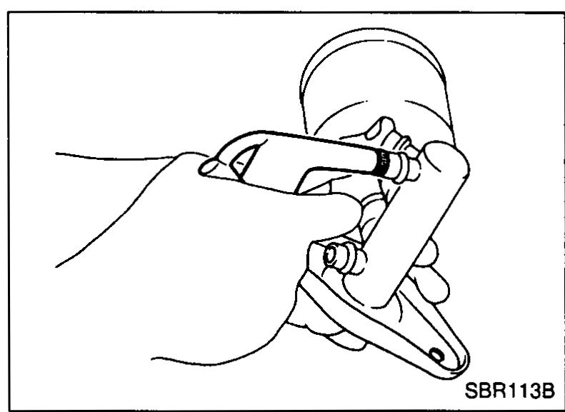 Illustration of technician using compressed air gun to apply pressure through fluid outlet to remove secondary piston assembly while wearing protective equipment.
