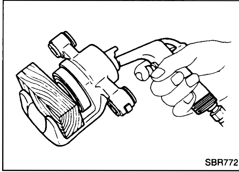 Disassembly step 1: hand-held cylinder body with a compressed-air nozzle blowing through the bleed-port to push piston (with dust seal) out of the cylinder.