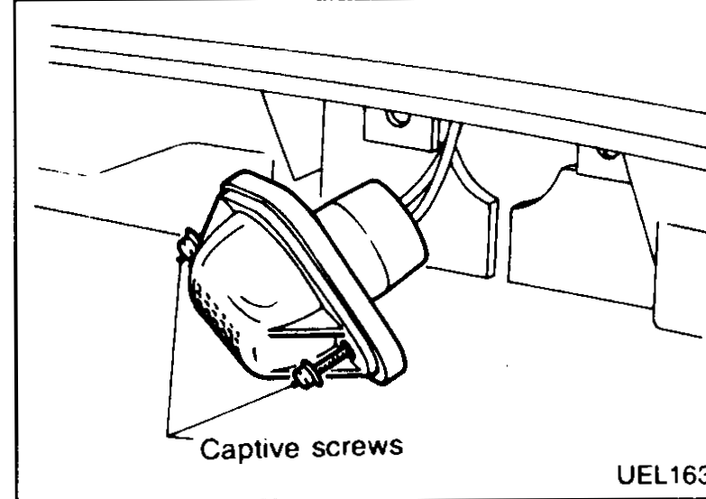 License plate lamp shown with lens cover and captive screws beneath the rear bumper.