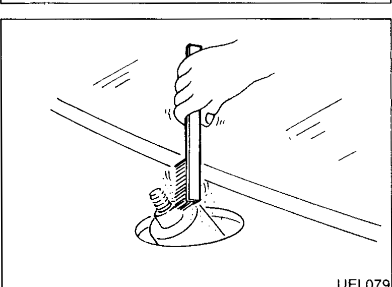 Close-up of rear wiper arm pivot showing the wiper arm nut cover lifted and the wiper arm nut beneath it.