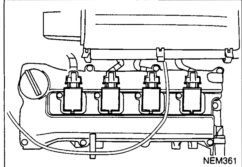 Photograph of the rocker cover area showing the four ignition coils installed on the cylinder head, illustrating the locations to disconnect prior to spark plug removal.