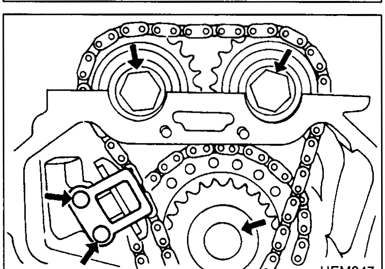 Timing chain area showing camshaft sprockets, idler sprocket and chain tensioner. Arrows indicate the bolts and tensioner to be removed.