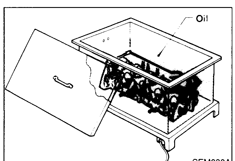Cylinder head submerged in an oil bath on a stand prior to pressing the service valve seat in; label "Oil" points at the bath.