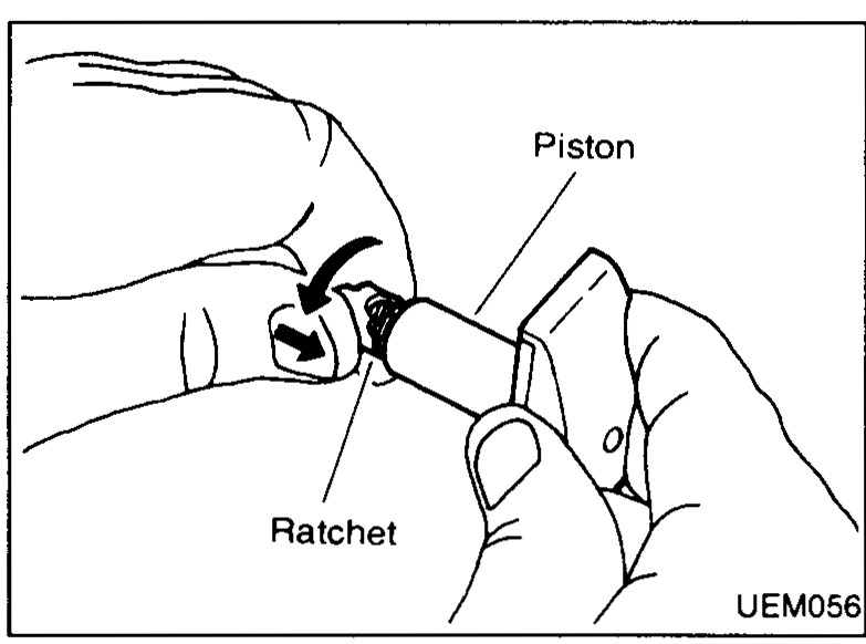 Two hands holding the chain tensioner assembly with one hand rotating/pushing the ratchet up the spiral on the piston shaft to pre-set the tensioner. Callouts: "Piston", "Ratchet".