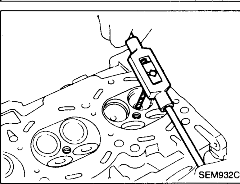 Hammer driving a punch/drift into a valve guide on the cylinder head combustion-chamber face to press the old valve guide out. Asterisks (★) on the head indicate heated areas.
