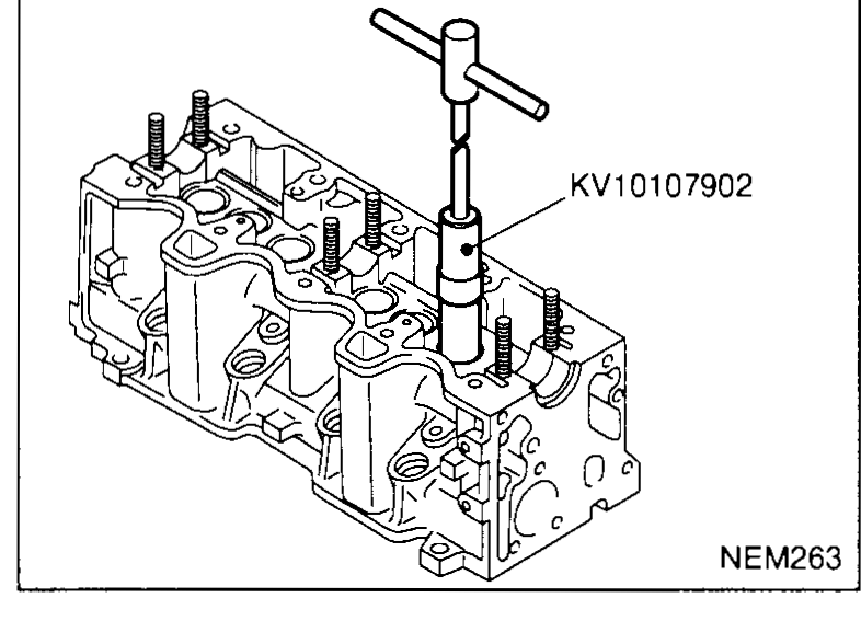 Cylinder head on bench with the KV10107902 valve oil seal puller engaged on a valve stem seal — illustrates disassembly step 7.