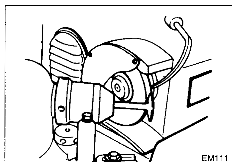 Bench-mounted valve grinder being used to grind a valve face — illustrates step 3 (reface valve face/stem end with valve grinder).