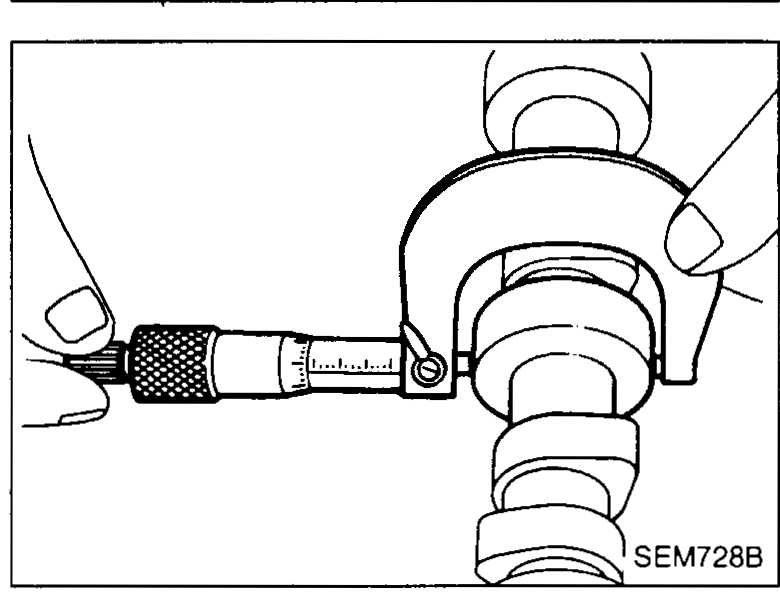 Cylinder head on bench with hand using an inside-micrometer / bore gauge to measure the camshaft bearing inner diameter — illustrates camshaft-journal-clearance step 1.