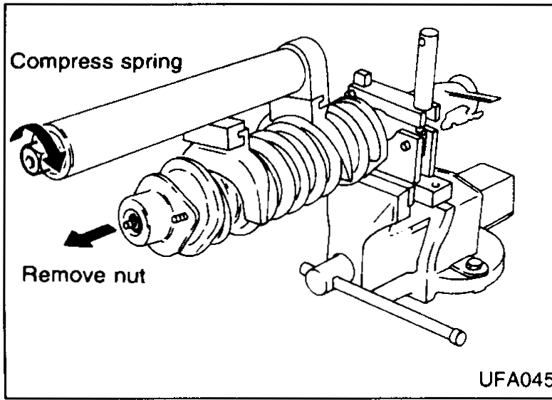 Photo of the strut lower bracket meeting the knuckle with two arrows pointing at the strut lower fixing bolts to be removed.