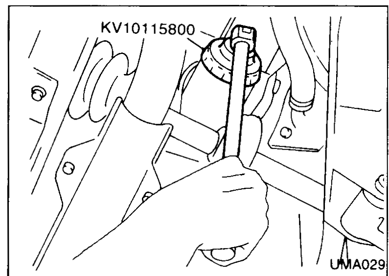 Oil filter wrench (Tool KV10115800) being used to remove an oil filter from underneath the engine.
