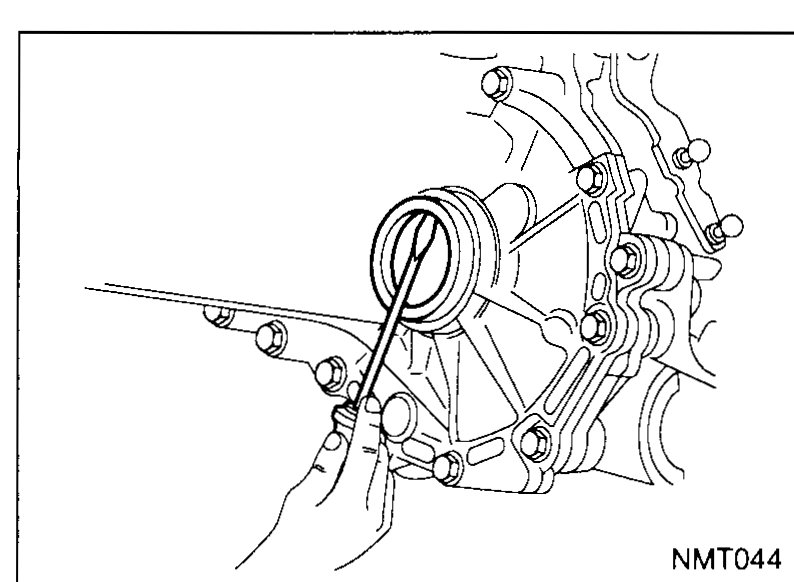 Hand using a drift through the differential opening of the transaxle case to remove the old differential oil seal.