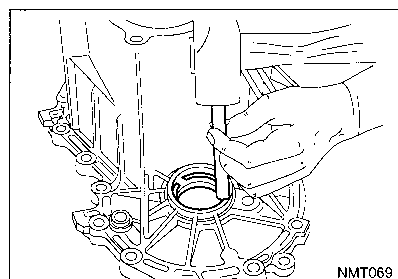 Mechanic drifting out the differential left-hand side bearing outer race from the clutch housing using a long drift.