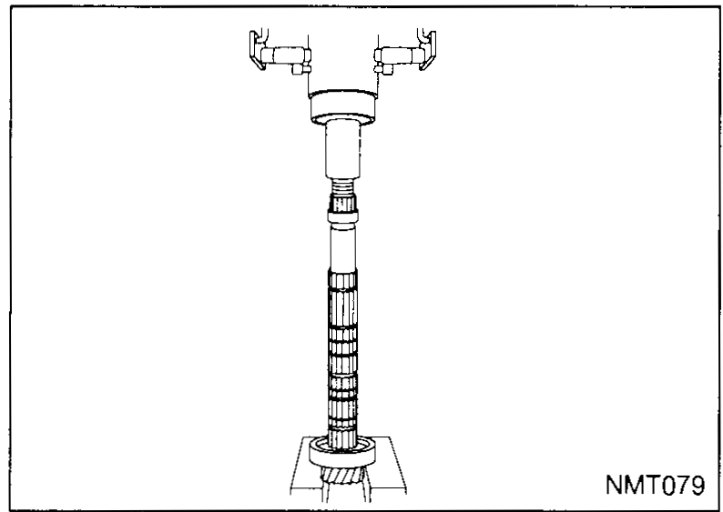 Mainshaft mounted vertically on a bearing puller stand; the front bearing is being pressed off the lower end.