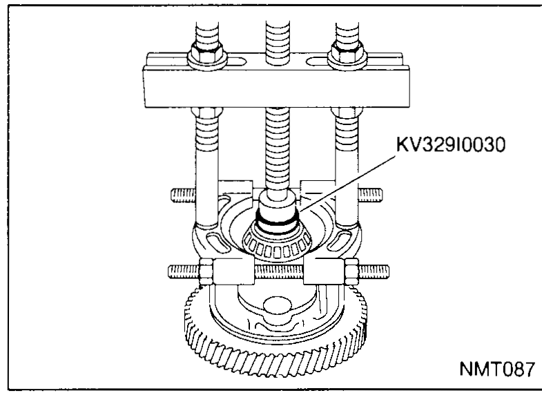 Differential case with the speedometer drive gear at the top being removed; a flat-blade lever / pry tool inserted between the speedometer gear and case from the upper-left.