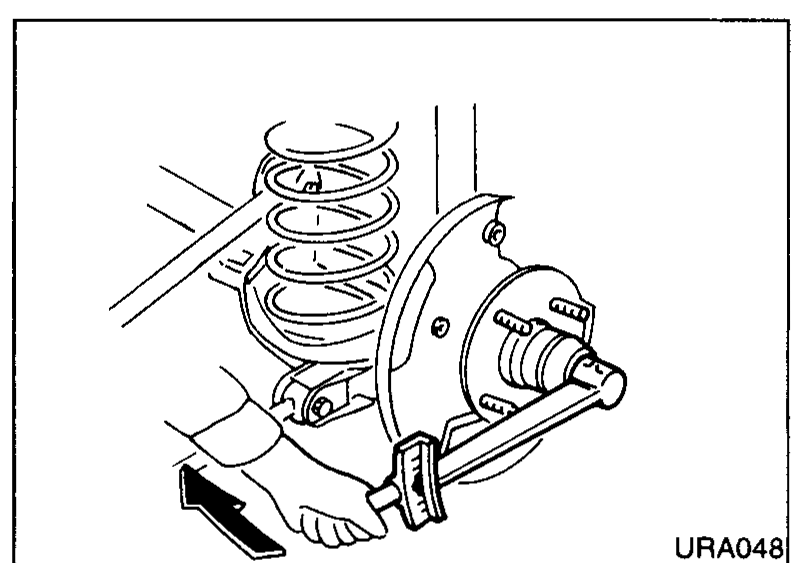 Mechanic pushing the rear wheel-hub bearing onto the stub axle with both hands; the coil spring is visible above. Used to illustrate hub-bearing installation.